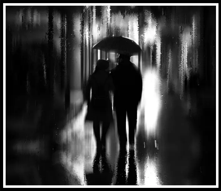 A couple walking in the rain with an umbrella.