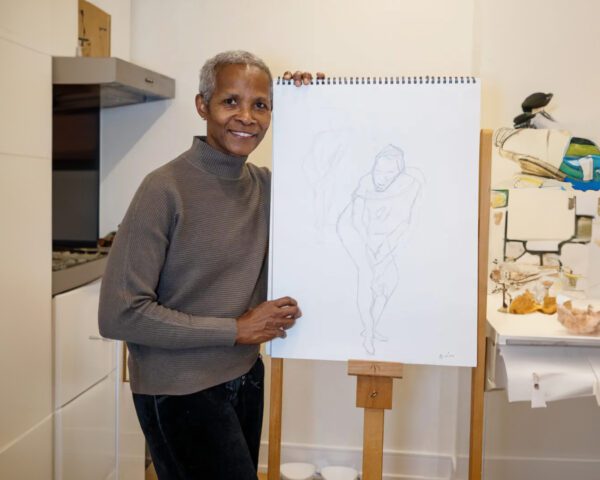 Black woman holding a drawing of a nude figure.