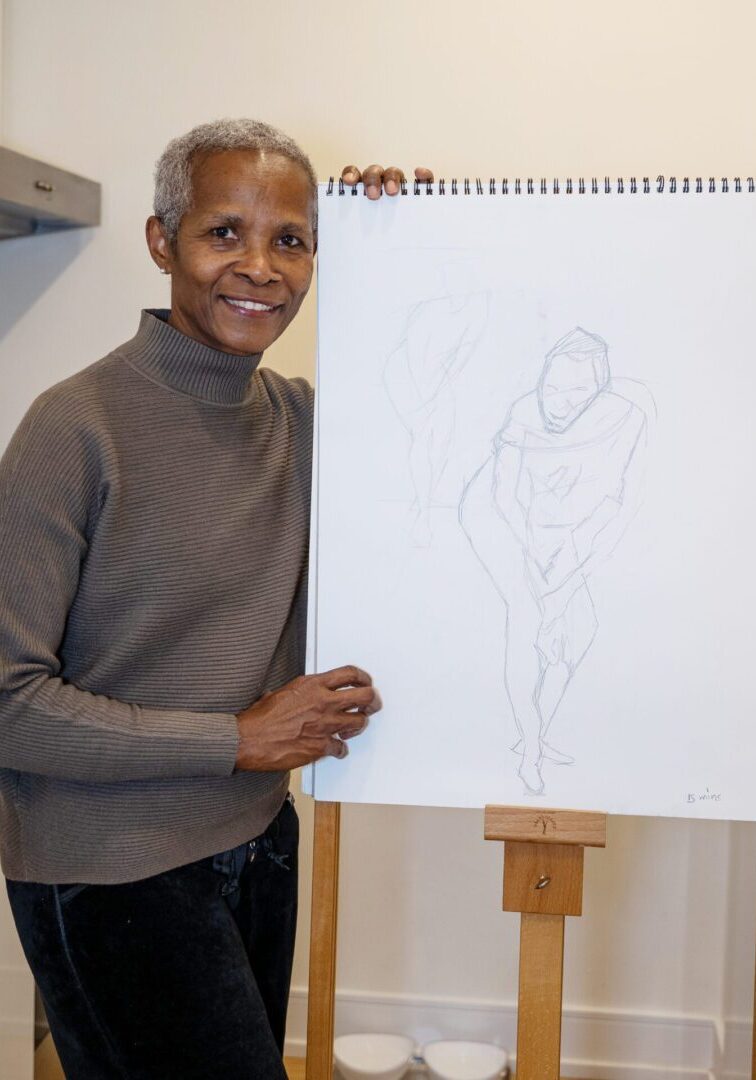 A woman holding an empty easel with a drawing of a man.